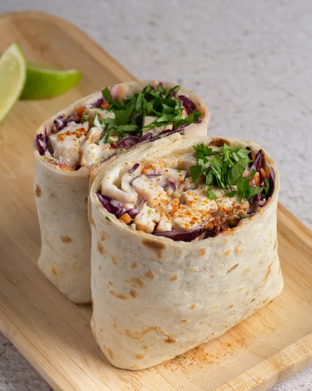Two hand-rolled burritos on a wooden board