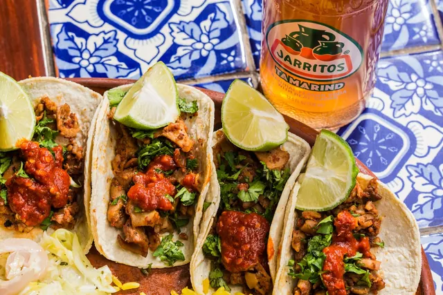 Mexican tacos with salsa and a bottle of Jarritos